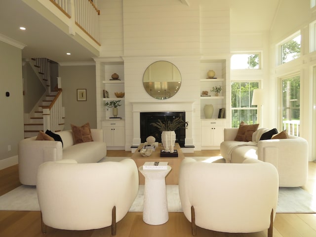 18 Pleasant Park Dr, Mashpee, MA 02649 - living area with a high ceiling, light wood-style floors, stairway, a large fireplace, and crown molding