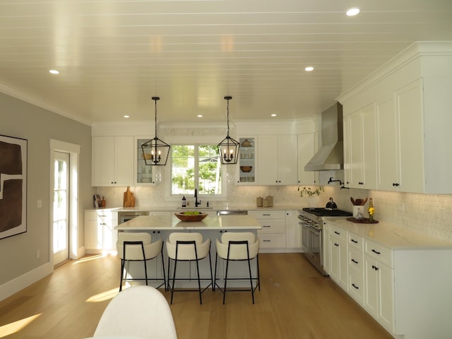 18 Pleasant Park Dr, Mashpee, MA 02649 - kitchen with high end range, wall chimney exhaust hood, a breakfast bar, light wood-type flooring, and white cabinetry