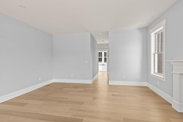 unfurnished room featuring a fireplace, light wood-type flooring, and a wealth of natural light