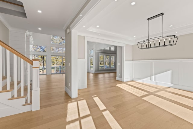 foyer entrance with light wood-type flooring, a raised ceiling, and ornamental molding