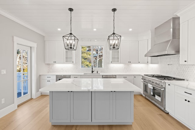 kitchen with light stone counters, appliances with stainless steel finishes, a center island, and wall chimney exhaust hood