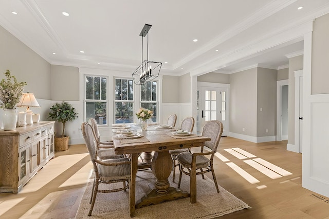 dining area featuring light hardwood / wood-style flooring, crown molding, and a chandelier