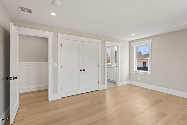 unfurnished bedroom with connected bathroom, a closet, and light wood-type flooring