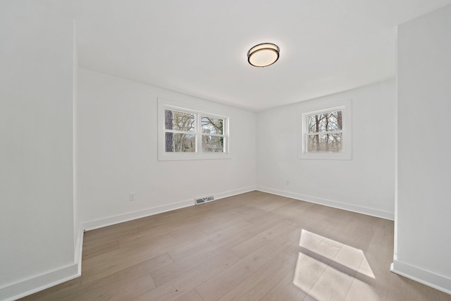 unfurnished room with plenty of natural light, wood finished floors, and baseboards