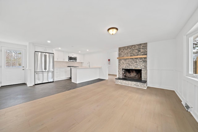 unfurnished living room featuring dark wood finished floors, a brick fireplace, recessed lighting, and a sink