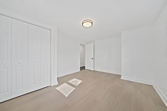 unfurnished bedroom featuring wood finished floors, baseboards, and a closet