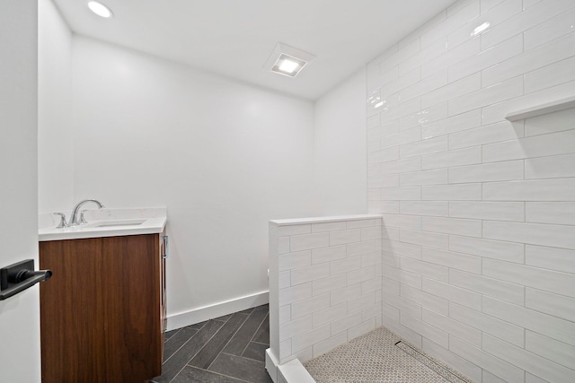 bathroom with vanity, baseboards, recessed lighting, and a tile shower
