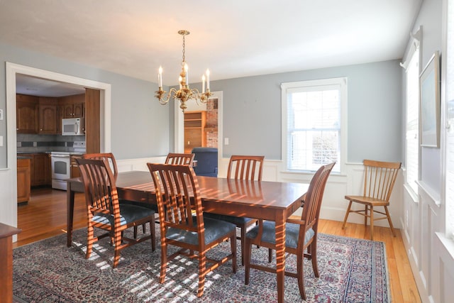 dining area with a wealth of natural light, an inviting chandelier, and light hardwood / wood-style floors