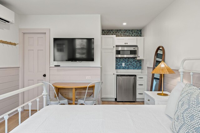 72 Forest Beach Rd, South Chatham, MA 02659 - bedroom featuring a wall mounted air conditioner, wood finished floors, fridge, recessed lighting, and a wainscoted wall