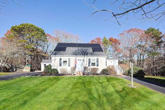 view of front of property with a front lawn and solar panels