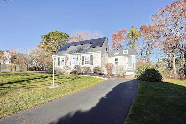 view of front of property featuring solar panels and a front lawn