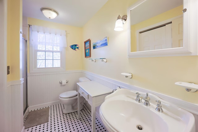 bathroom featuring toilet, walk in shower, wooden walls, tile patterned flooring, and sink