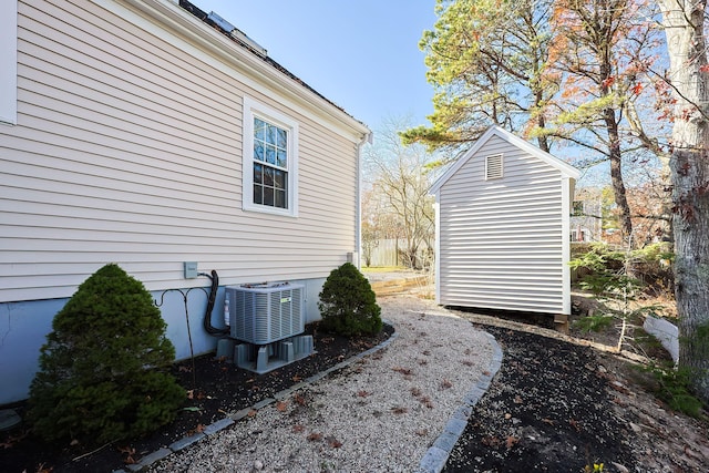 view of side of property with a storage shed and central AC