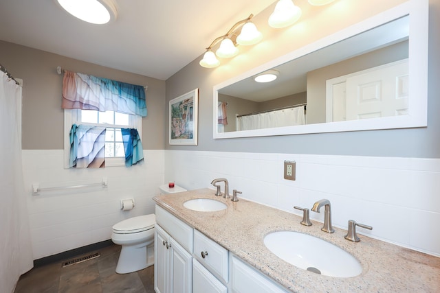 bathroom with tile walls, toilet, and vanity