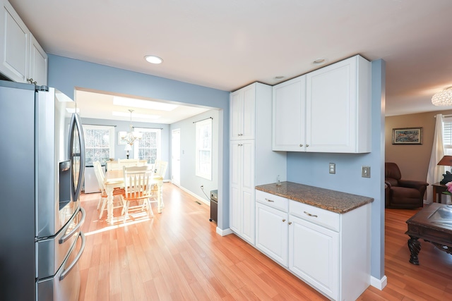 kitchen featuring white cabinets, decorative light fixtures, light hardwood / wood-style floors, and stainless steel refrigerator with ice dispenser