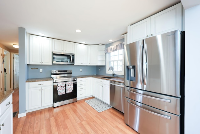 kitchen with sink, light stone counters, white cabinets, and appliances with stainless steel finishes