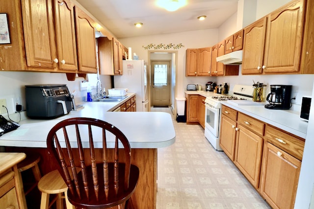 62 Jernegan Ave, Edgartown, MA 02539 - kitchen featuring white appliances, under cabinet range hood, a sink, light countertops, and a breakfast bar area