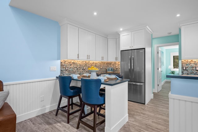 290 Fletcher Ln, Brewster, MA 02631 - kitchen featuring stainless steel fridge, dark countertops, white cabinetry, recessed lighting, and a wainscoted wall