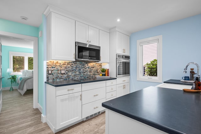 290 Fletcher Ln, Brewster, MA 02631 - kitchen featuring appliances with stainless steel finishes, dark countertops, light wood-type flooring, tasteful backsplash, and white cabinets
