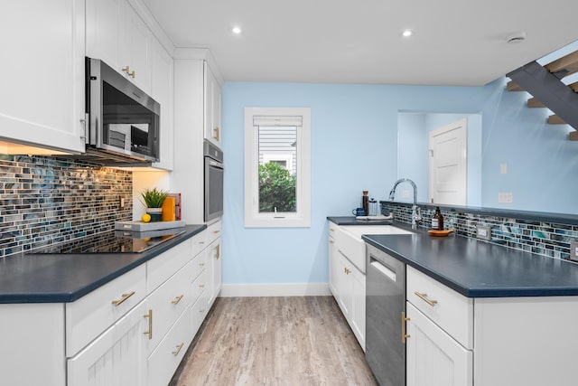 290 Fletcher Ln, Brewster, MA 02631 - kitchen featuring appliances with stainless steel finishes, dark countertops, decorative backsplash, a peninsula, and light wood finished floors