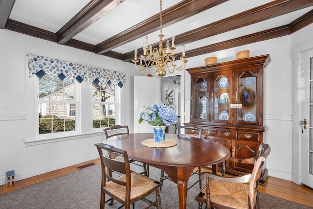 dining space with a notable chandelier, beam ceiling, visible vents, and wood finished floors