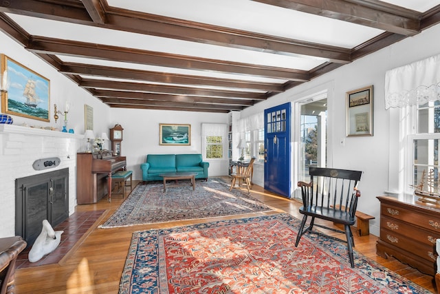 living area featuring beam ceiling, a fireplace, and wood finished floors