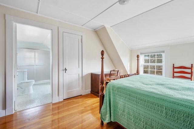 bedroom featuring lofted ceiling, connected bathroom, and light wood-style flooring