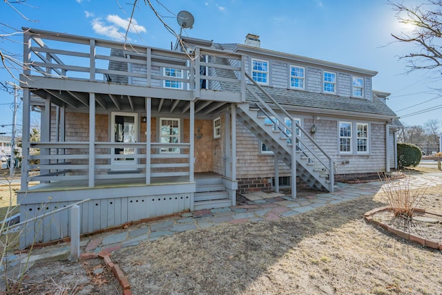 back of house featuring a shingled roof, stairway, and a chimney