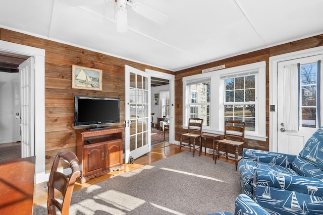 living room featuring wooden walls, french doors, wood finished floors, and a healthy amount of sunlight