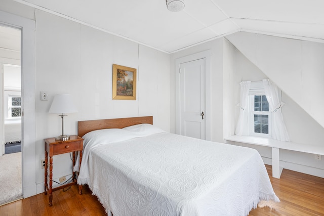 bedroom with vaulted ceiling and wood finished floors