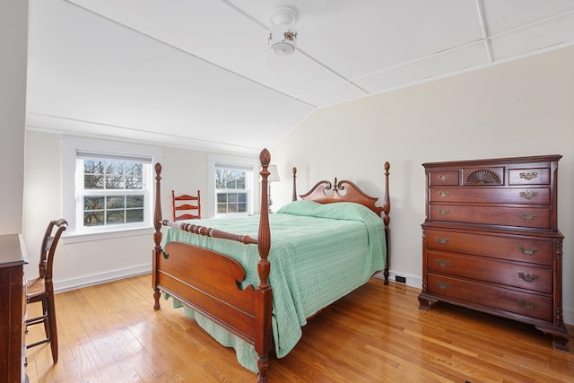 bedroom featuring light wood-style flooring, baseboards, and vaulted ceiling