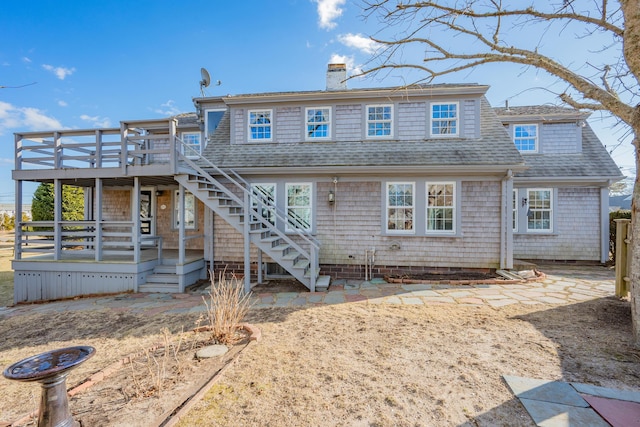 view of front of home featuring a shingled roof, stairway, a chimney, and a wooden deck