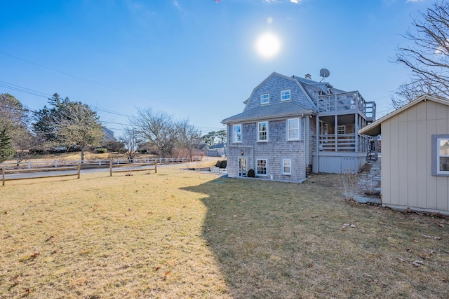 back of property featuring a yard, fence, an outbuilding, and a gambrel roof