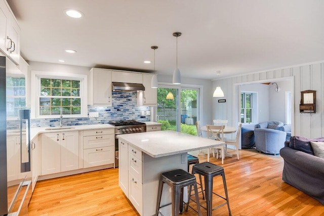 22 Emerson Rd, East Falmouth, MA 02536 - kitchen with high end stainless steel range, open floor plan, a kitchen breakfast bar, ventilation hood, and backsplash