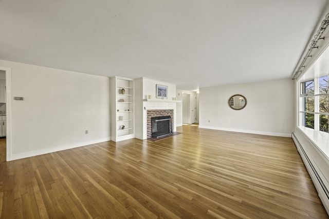 unfurnished living room featuring a baseboard radiator, baseboards, wood finished floors, and a fireplace