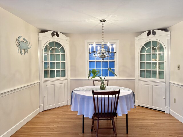 dining room with breakfast area, light wood-type flooring, baseboards, and an inviting chandelier