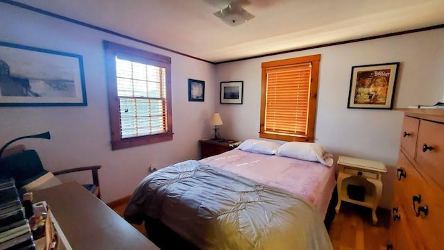 bedroom with ornamental molding and wood finished floors