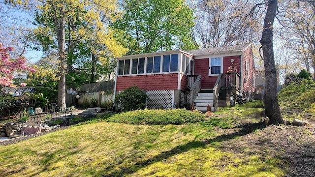 view of front facade featuring a sunroom, a front lawn, and fence