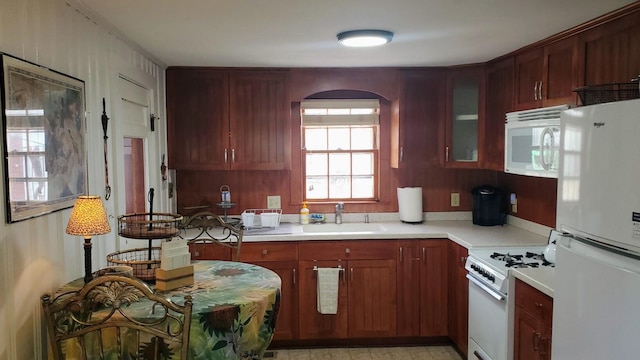 kitchen with white appliances, light countertops, a sink, and glass insert cabinets