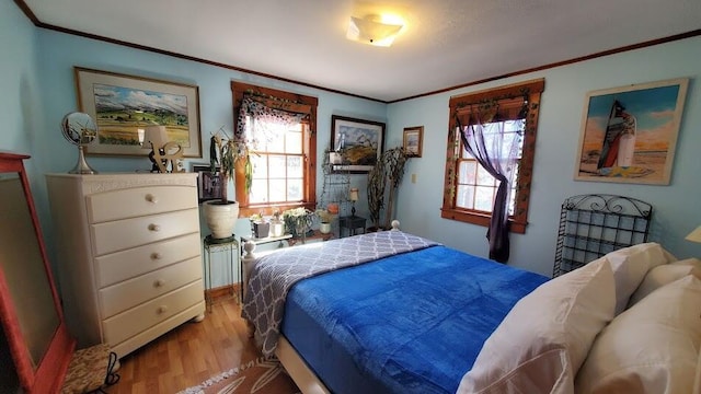 bedroom with crown molding, light wood-style flooring, and multiple windows