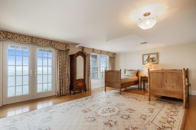 bedroom featuring ornamental molding, wood finished floors, french doors, and visible vents