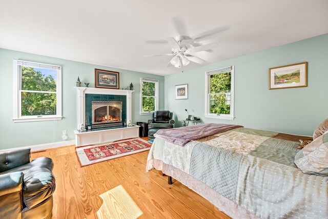 319 Riverview Dr, Chatham, MA 02633 - bedroom featuring a tiled fireplace, wood finished floors, baseboards, and a ceiling fan