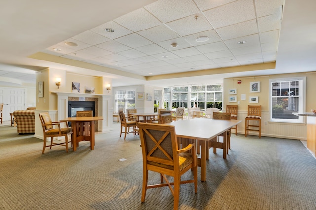 110 Dillingham Ave Unit 212U, Falmouth, MA 02540 - dining area with carpet flooring, a paneled ceiling, a tray ceiling, a glass covered fireplace, and a wainscoted wall