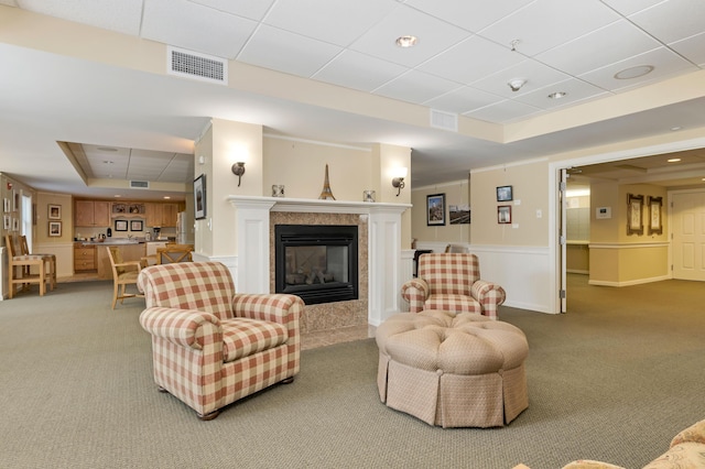 110 Dillingham Ave Unit 212U, Falmouth, MA 02540 - living room featuring a tray ceiling, light colored carpet, a tile fireplace, a paneled ceiling, and wainscoting