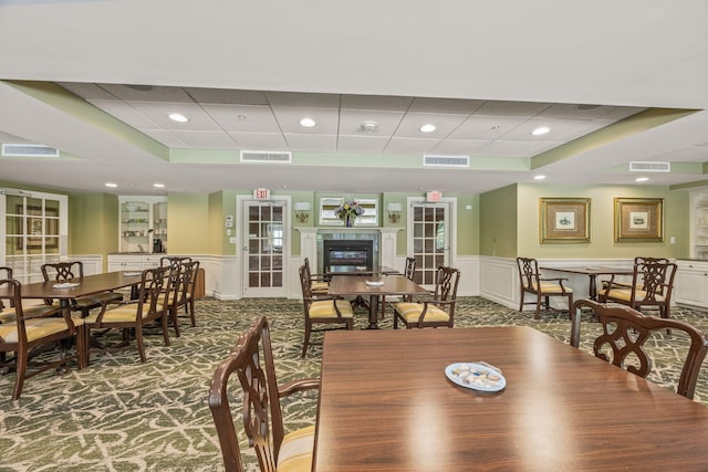 110 Dillingham Ave Unit 212U, Falmouth, MA 02540 - dining area featuring carpet floors, wainscoting, a paneled ceiling, a decorative wall, and a glass covered fireplace