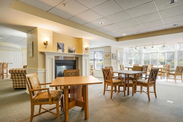 110 Dillingham Ave Unit 212U, Falmouth, MA 02540 - dining space with light carpet, a tile fireplace, a decorative wall, a paneled ceiling, and wainscoting