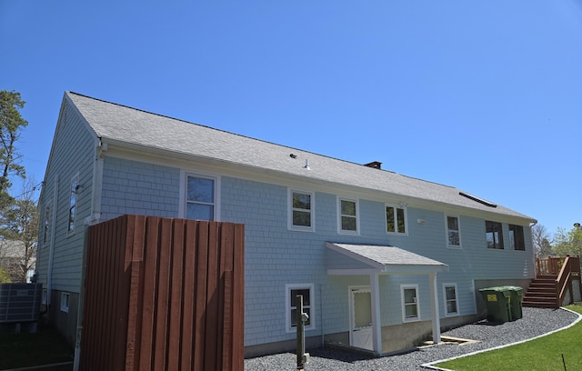 back of house featuring stairs, roof with shingles, and cooling unit