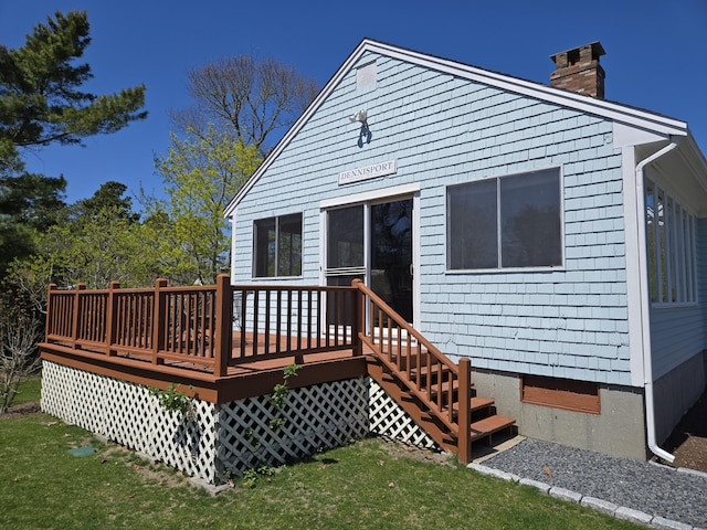 rear view of property featuring a chimney, a yard, and a deck