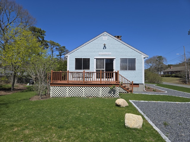 rear view of house with a yard, a wooden deck, and a chimney