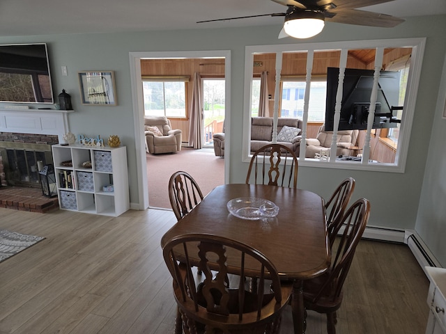 dining room featuring ceiling fan, wood finished floors, a wealth of natural light, and a fireplace